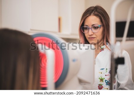 an optometrist uses a wide cone corneal topographer to take information from a patient's cornea. Royalty-Free Stock Photo #2092471636