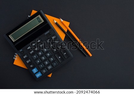 Top view of calculator, pencil and notebook on the black background. Copy space. Workspace desk.