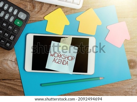 Handwriting text Workshop Agenda. Word Written on helps you to ensure that your place stays on schedule Display of Different Color Sticker Notes Arranged On flatlay Lay Background