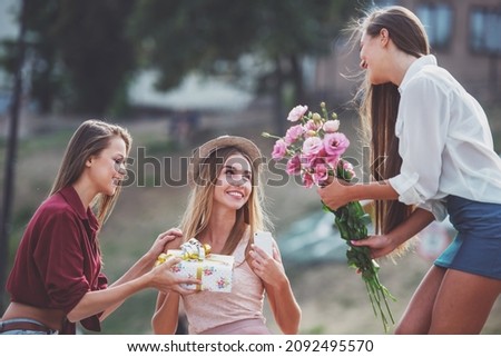 Three beautiful young women with flowers outdoors