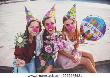 Three beautiful young women celebrating a birthday, outdoors