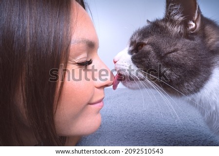 Cute cat licking or kissing woman's nose. Cat and owner together Royalty-Free Stock Photo #2092510543