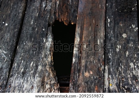 Photo of old wooden planks that are weathered and have holes