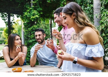 tequila shot, Group of Young latin Friends Meeting For tequila shot or mezcal drinks making A Toast In Restaurant terrace in Mexico Latin America Royalty-Free Stock Photo #2092575823