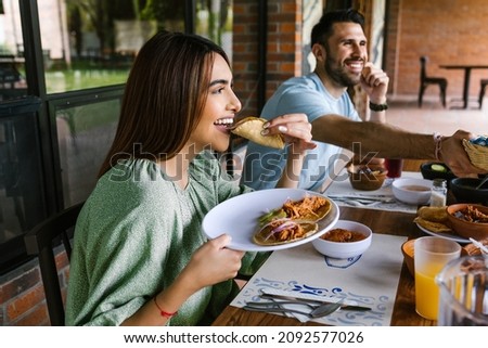 young latin woman eating mexican tacos on a restaurant terrace in Mexico Latin America, feeling happy on a summer day Royalty-Free Stock Photo #2092577026