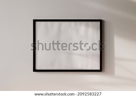Black photo frame mockup 4x3 on white wall