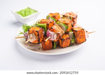 Paneer tikka is an Indian dish made from chunks of cottage cheese marinated in spices and grilled in a tandoor Royalty-Free Stock Photo #2092612759
