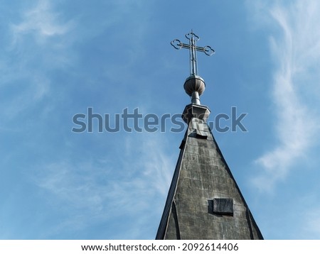 Shot of a church steeple with a cross against a cloudy sky
