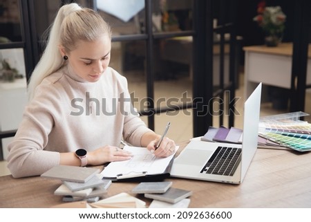 Portrait young woman professional designer develops design of apartment project in workplace laptop.