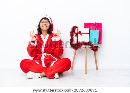 Young girl celebrating Christmas sitting on the floor isolated on white bakcground in zen pose