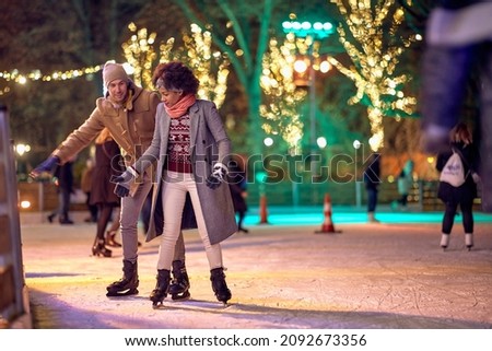 Joyful multiethnic couple enjoying night ice skating together