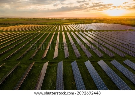 Aerial view of large sustainable electrical power plant with many rows of solar photovoltaic panels for producing clean electric energy at sunset. Renewable electricity with zero emission concept. Royalty-Free Stock Photo #2092692448