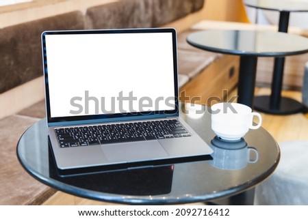 Blank screen laptop computer modern man use room laptop with blank white desktop screen with coffee cup on wooden table in cafe