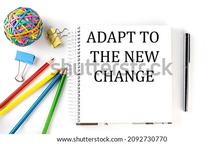 Notebook ,pencils,pen and rubber band with text ADAPT TO THE NEW CHANGE on white background
