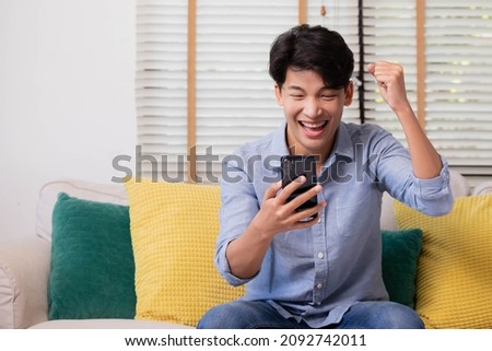 Asian man making facetime video calling with smartphone at home. He's waving on phone screen. Using conferencing meeting online app. Royalty-Free Stock Photo #2092742011