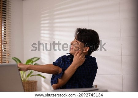 After working and researching online on a desk with a laptop, an Asian businessman flexes his arm. Royalty-Free Stock Photo #2092745134