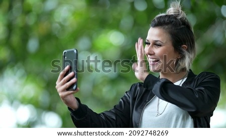 Young woman talking on smartphone camera with friends, long distance