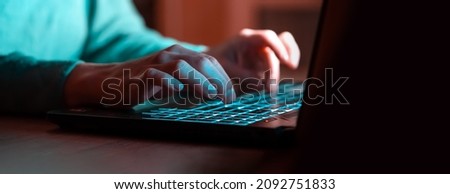 A girl works at a laptop at night online, texting, looking for information, studying, female hands on the keyboard close-up.