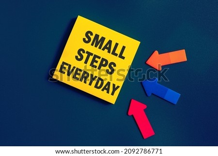 Small steps everyday - text on sticky note paper on blue background. Closeup of a personal agenda. Top view. Conceptual photo