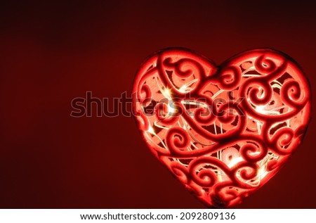 The lighted red heart is on dark red background with yellow lights inside,