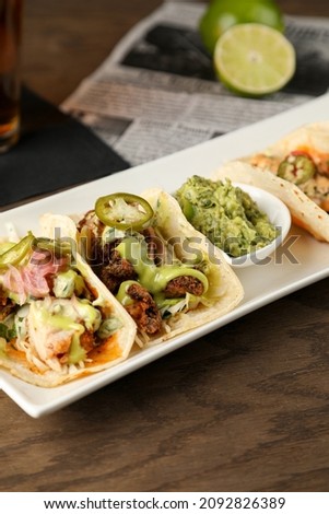 Mexican tacos with fish barbecue and carnitas shot in panoramic composition on top of serving white plate

