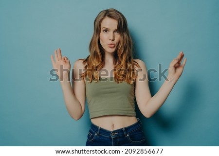 Young confident european woman showing okay gesture with both hands and pouting lips isolated over pastel blue studio wall background, female saying that everything is fine. Body language concept