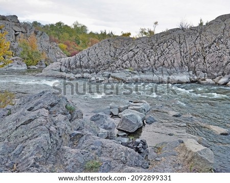 Whitewater rapids of the Southern Buh River taken with a slow shutter speed, granite rocks and fall colors of trees in the nature reserve of Granite-Steppe Lands of Buh, Mykolaiv Region, Ukraine