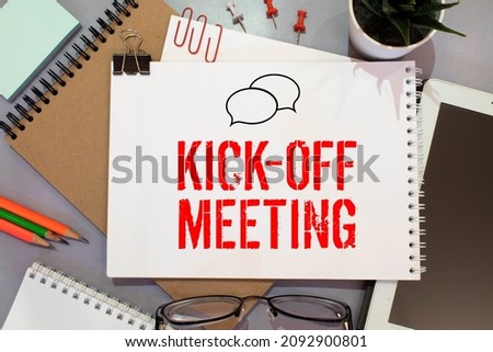 kickoff meeting, text on notepad sheet on brown background near magnifier and coffee cup. Royalty-Free Stock Photo #2092900801