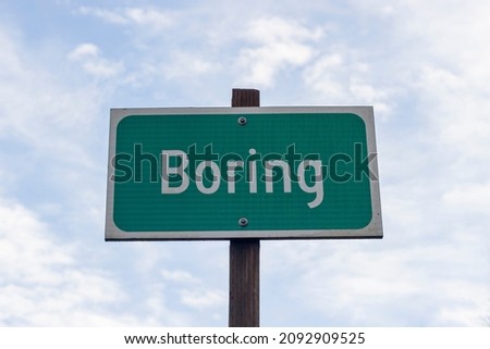 Closeup of the city limit sign of Boring, Oregon, against blue sky and clouds. Boring (Oregon) and Dull (Scotland) became sister communities in 2012, united by unexciting names.