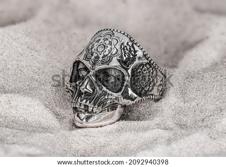 Jewelry made of silver rings in the form of a skull on the sand