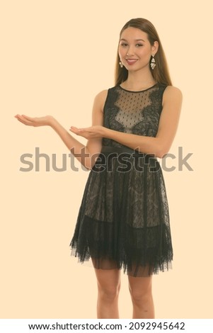 Studio shot of young beautiful Asian woman isolated against white background
