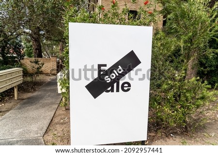 White for sale sign near the resedential appartment building with sold sticker on it. Real estate property investment boom