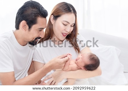 Happay family with newborn child. Newly father and mother excited having first baby, family holding and smiling to their baby.