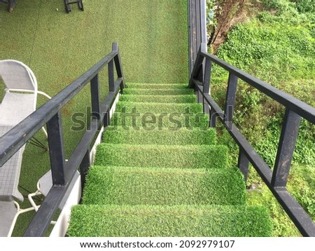 Photo of stair case was cover with artificial grass in the park .