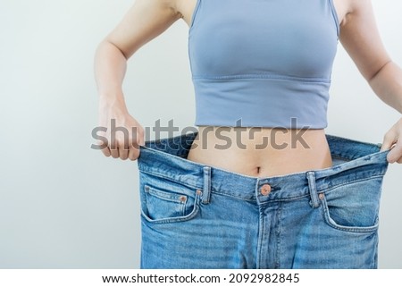 Shape slender, thin waist, attractive slim asian young woman, hand show shape her weight loss, wearing in big, large or oversize jeans, excess lose by diet and exercise. People body fit healthy. Royalty-Free Stock Photo #2092982845