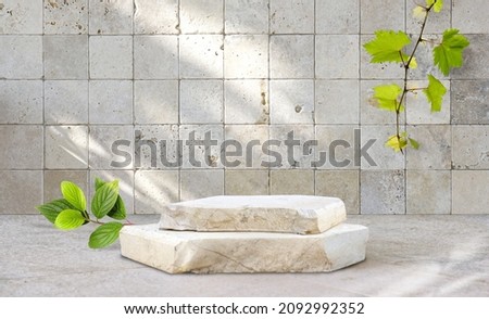 Original template for spa product presentation. Pedestal of marble slabs and branches with green leaves  against  background of wall in bathroom with masonry in light beige colors. Royalty-Free Stock Photo #2092992352