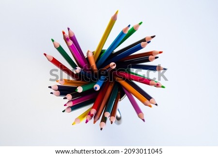 Colored plastic pencils in a steel lid are positioned with leads up. Form a colored spiral.