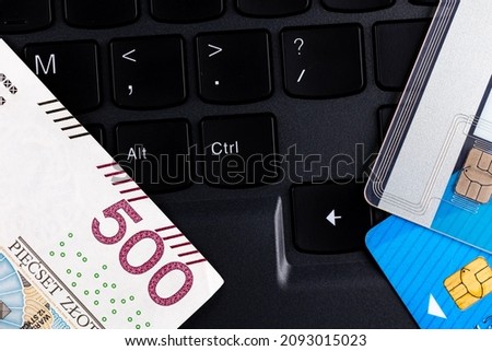 Polish 500 PLN banknote and credit cards arranged on the laptop keyboard. Cybersecurity of online shopping. Photo taken under artificial, soft light