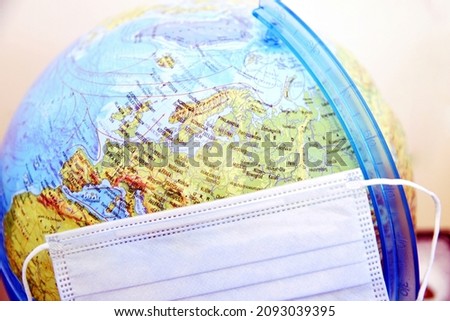 Illustrative photo of Covid-19 pandemic. Disposable mask and globe showing Europe. 