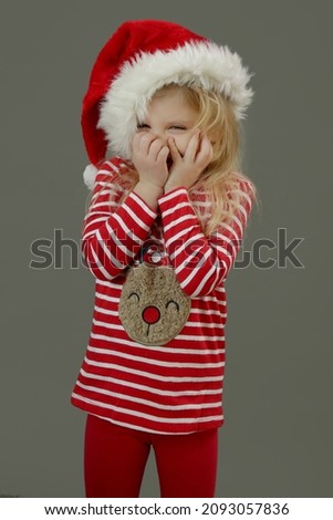 Studio portrait of sweet 4 years old girl in Santa hat and festive Christmas clothes. It's holiday season!	
