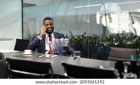Wealthy black guy in suit entrepreneur having phone conversation with his assistant or business partner, sitting at table with digital tablet on, looking at documents, panorama with copy space Royalty-Free Stock Photo #2093061292