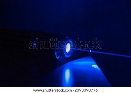 Powerful laser pointer, blue laser capable of burning paper and leaving burns, modern laser technology Royalty-Free Stock Photo #2093090776