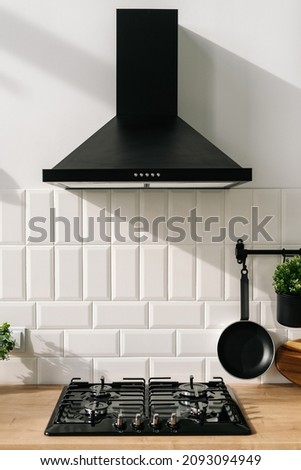 Closeup of modern kitchen interior in white and black tones with frying pan, stove and extractor closeup. Cozy place for cooking concept. Modern household appliances  Royalty-Free Stock Photo #2093094949