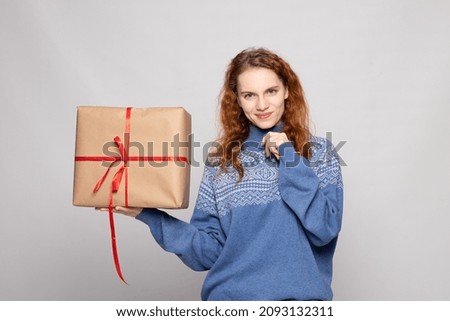 young girl in a sweater is holding a gift on a white background