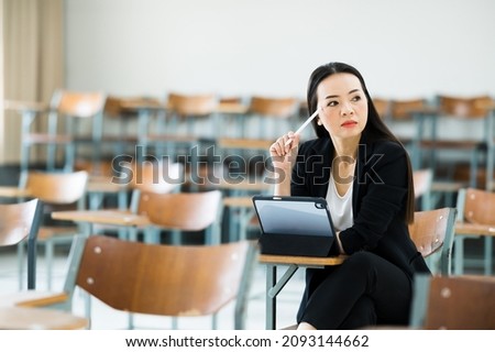 A female teacher with a tablet sits in an empty classroom at the university. while waiting to teach the students at the class