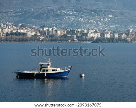 Small fishing boat moored in front of the city of Lecco, on Lake Como (Italy)