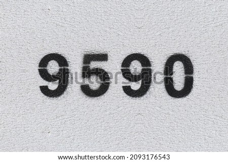 Black Number 9590 on the white wall. Spray paint. Number nine thousand five hundred ninety.
