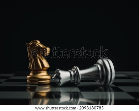 The golden horses, knight chess piece standing near the loser silver queen chess piece who fell on chessboard background. Leadership, winner, loser, competition, and business strategy concept. Royalty-Free Stock Photo #2093180785