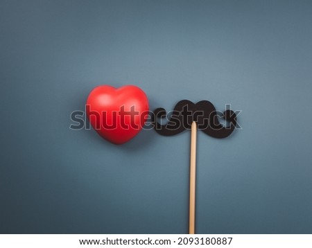 Red heart ball and mustache stick isolated on blue background, minimal style. Happy father's day concept. 