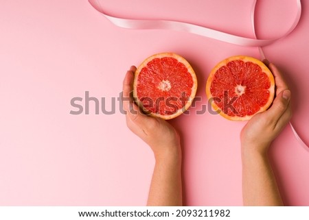 Young woman hands touching grapefruits and showing how to do a self-exam on the breasts to prevent cancer